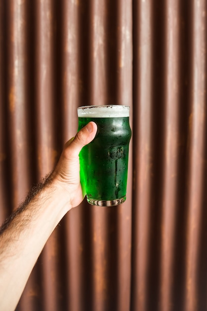 Free photo man with glass of green drink near wooden wall