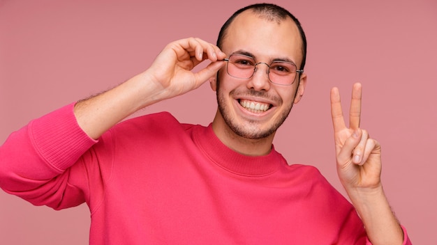 Free Photo man with glasses laughing and showing peace sign