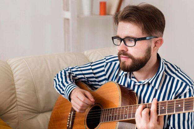 Man with glasses playing guitar at home