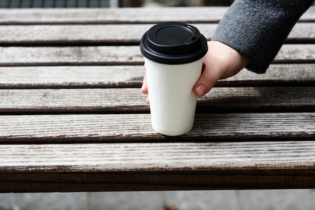 Free photo man with grey sleeve takes paper cup of coffee