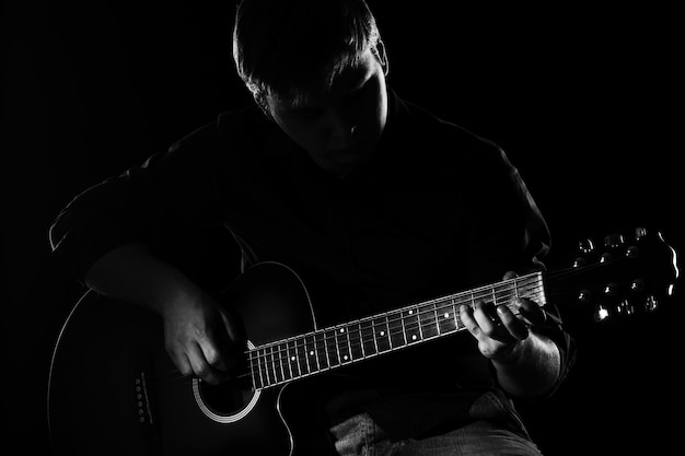 Man with guitar in darkness