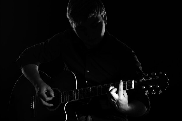 Man with guitar in darkness