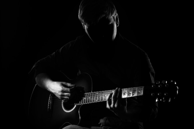 Free photo man with guitar in darkness