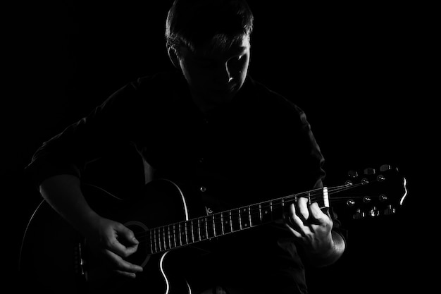 Man with guitar in darkness