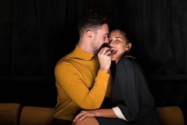 Man with hand near mouth of cheerful woman 