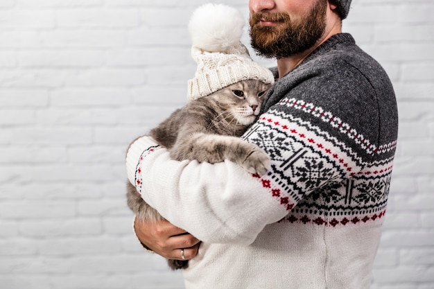 Free photo man with kitten wearing fur cap for winter