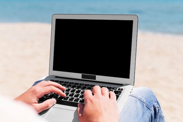 Man with laptop working at the beach