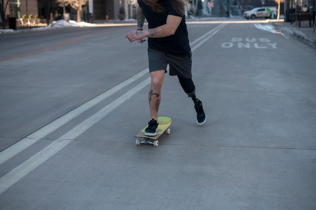 Free photo man with leg disability skateboarding in the city