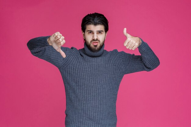 Man with long hair and beard making thumb up and down hand sign.