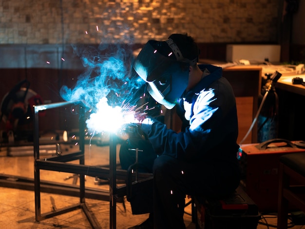 Man with mask welding metal in the atelier