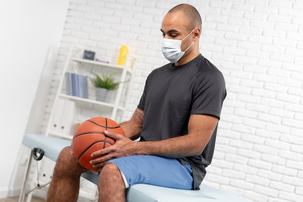 Free photo man with medical mask and basketball at physiotherapy