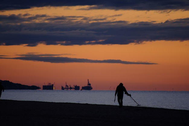 Free Photo man with metal detector in the morning, on the beach