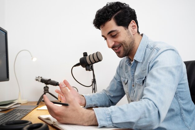 Man with microphone running a podcast in the studio and reading from papers