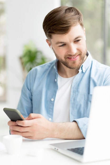 Man with mobile looking on laptop