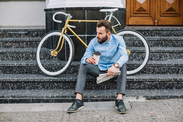 Free photo man with newspaper and hot beverage