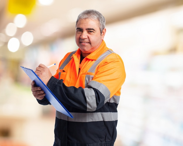 Man with an orange overalls taking note