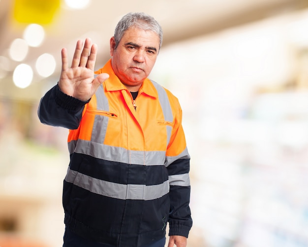 Free Photo man with an orange work jumpsuit making a "stop"