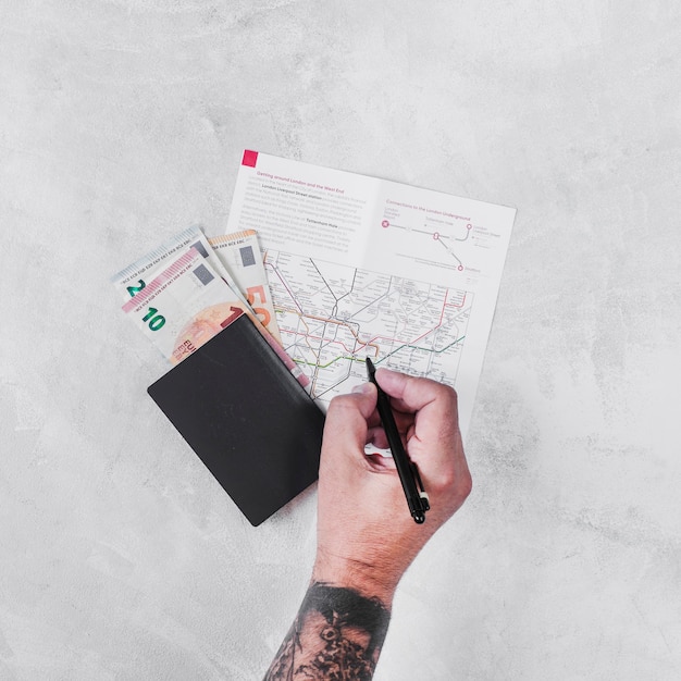 Man with passport and euro notes marking on road map