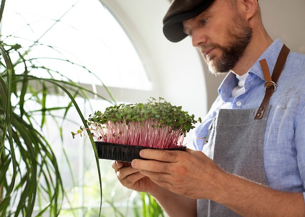 Free photo man with plants that have been cultivated and farmed indoors