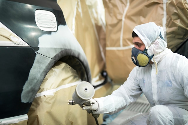 Free Photo man with protective clothes and mask painting automobile car bumper in repair shop