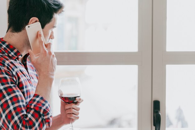 Man with red wine talking phone