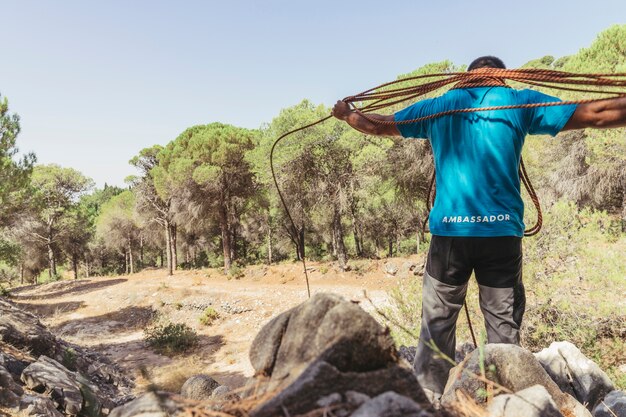 Man with rope around neck in forest