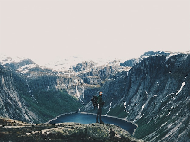 Free photo man with a rucksack admires gorgeous mountain landscape