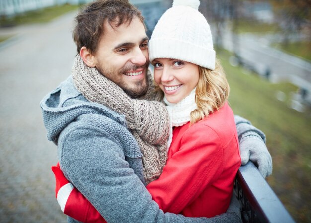 Free Photo man with scarf hugging his girlfriend outdoors