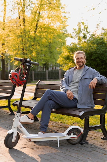 Free Photo man with scooter sitting on a bench