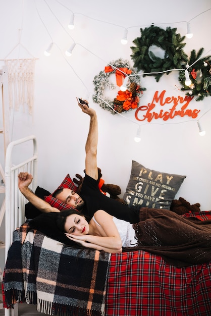 Man with smartphone and sleeping woman on bed