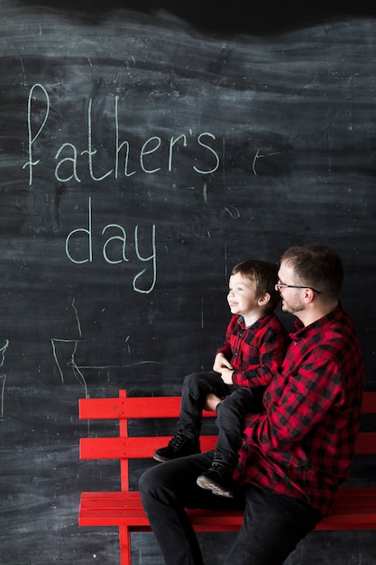 Free photo man with son on fathers day in front of blackboard