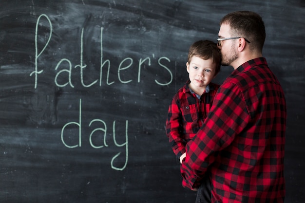 Free photo man with son on fathers day in front of chalkboard