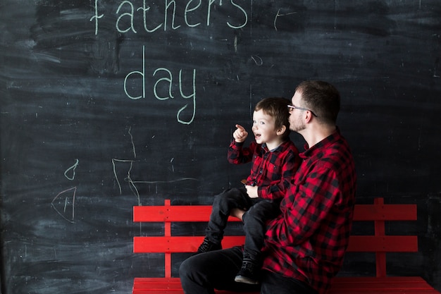 Free photo man with son on fathers day in front of chalkboard