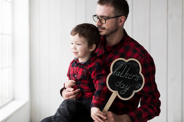 Free Photo man with son looking out of window on fathers day