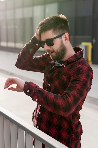 Free photo man with sunglasses holding head and looking at watches