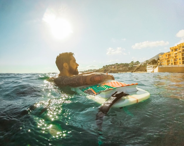 Free photo man with surfboard in blue water