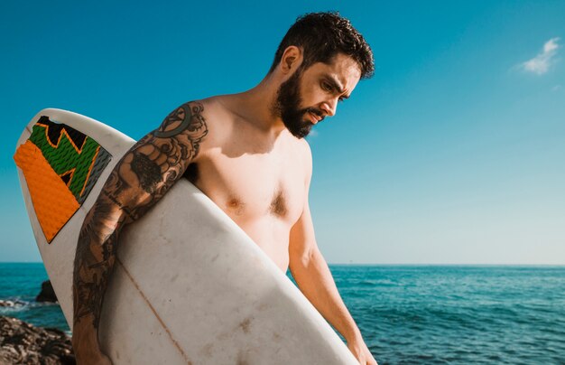 Man with surfboard walking near sea