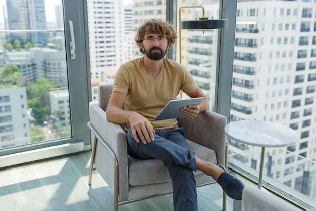 Free photo man with tablet sitting in sofa in modern office.