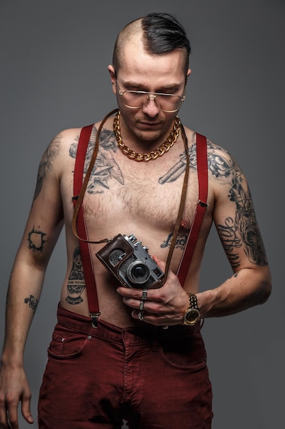 Free Photo man with tattoos on his body holding photo camera. isolated on grey.