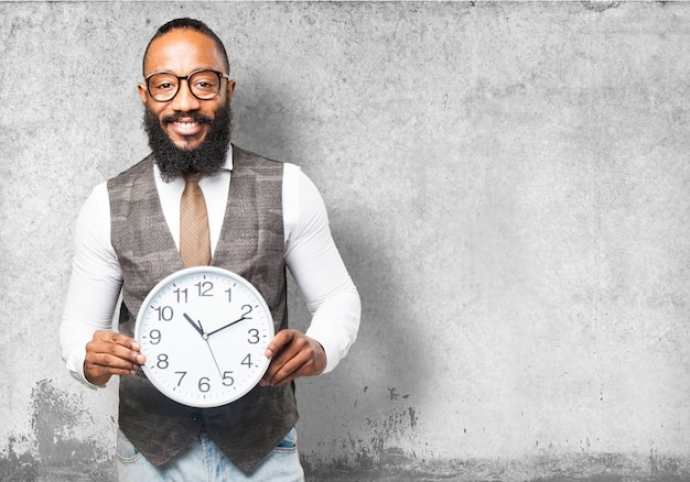 Man with tie smiling and holding a clock