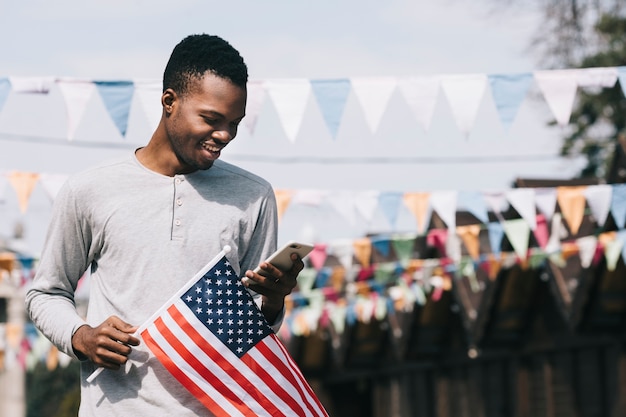 Free photo man with usa flag and smartphone