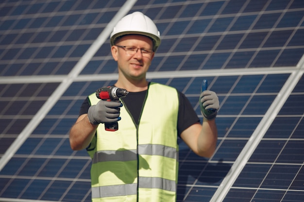 Man with white helmet near a solar panel