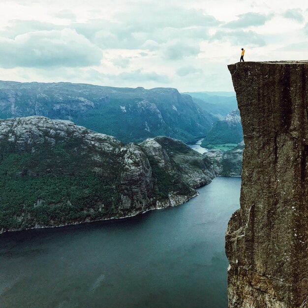 Man with a yellow jacket poses on the top of the rock