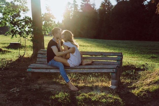 Free photo a man and a woman are sitting on a bench and kissing