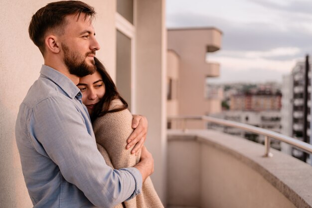 Free photo man and woman on balcony at sunset in the city