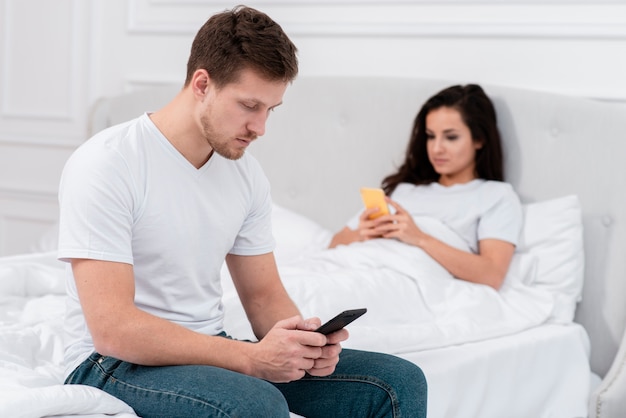 Man and woman checking their phone after waking up