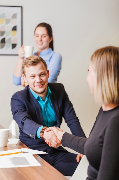 Free photo man and woman at desk shaking hands