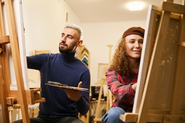 Free photo man and woman draw paintings on easels