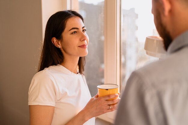 A man and woman drink tea near the window