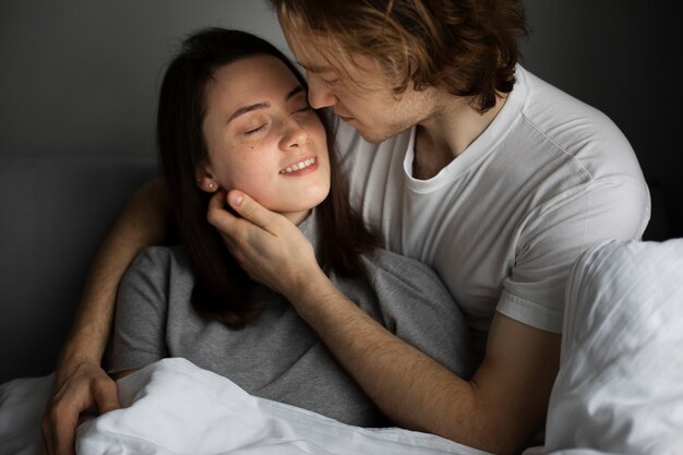 Man and woman embracing while smiling in bed